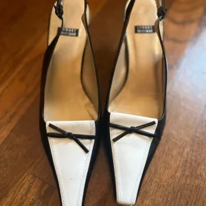 Stuart Weitzman Black and White Heels with Slingback Design and Pointed Toe .